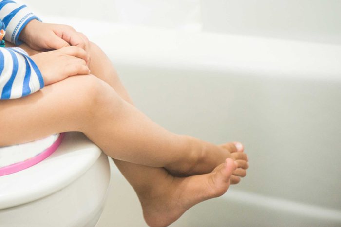 toddler sitting on a toilet and training seat