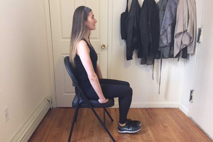 Woman doing seated knee lifts in a chair.