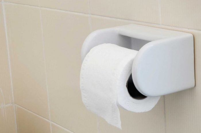 toilet paper hanging on roller in a tiled bathroom
