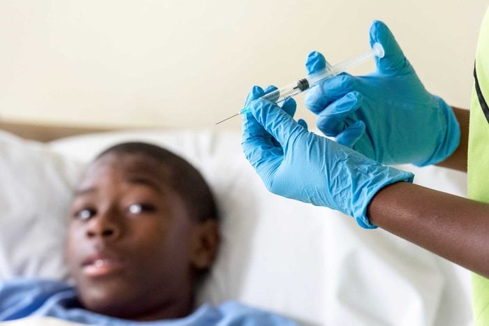African American young man looking warily at a syringe in a doctor's hands