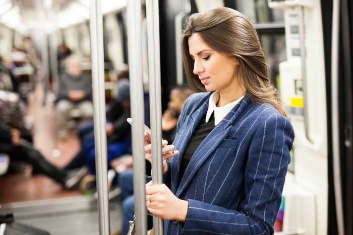 woman holding onto subway pole