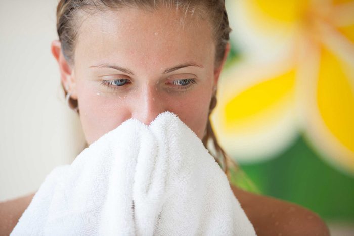 woman out of the shower, wiping her face with white towel