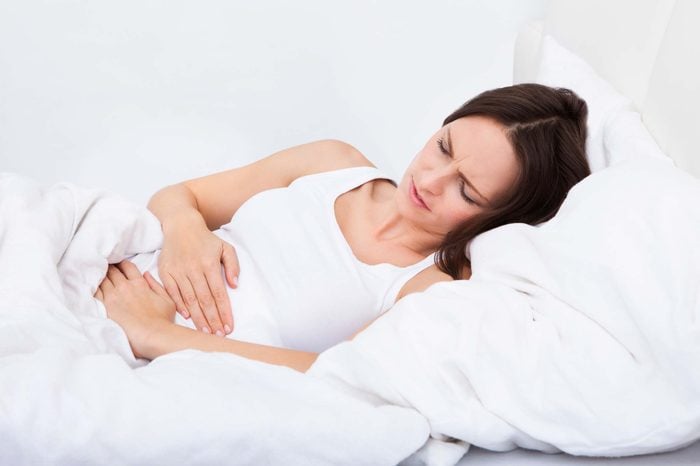 woman in bed holding stomach