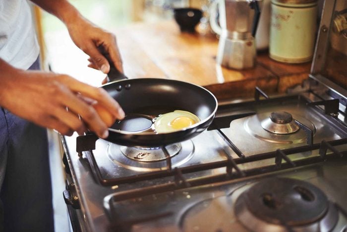 A man cooking eggs in a fry pan on the stove