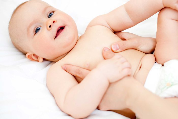hands massaging a baby's belly