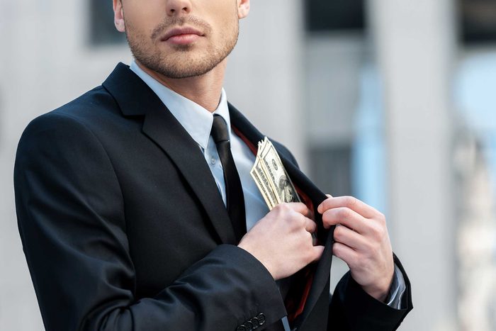 Man putting money into his inside suit pocket