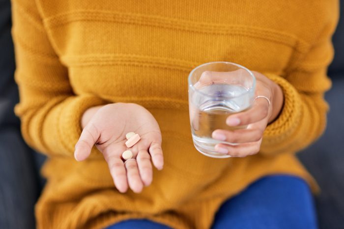 close up of woman holding a glass of water and medication