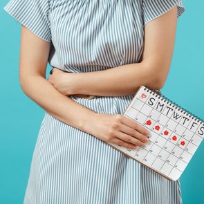 woman holding stomach with menstrual calendar period