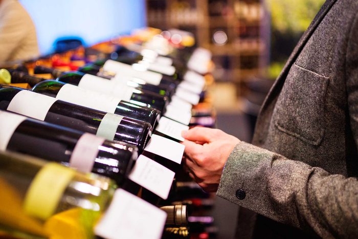 man checking prices on bottles of wine
