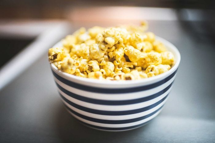 Bowl of yellow, buttery popcorn in a blue- and white-striped bowl.