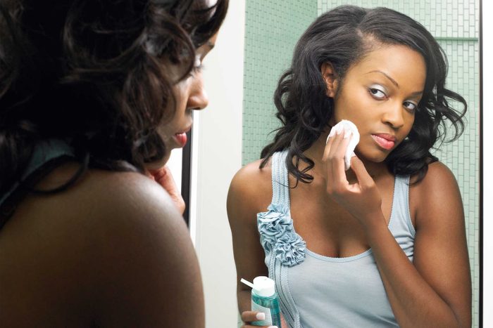 black woman checking her skin in the mirror