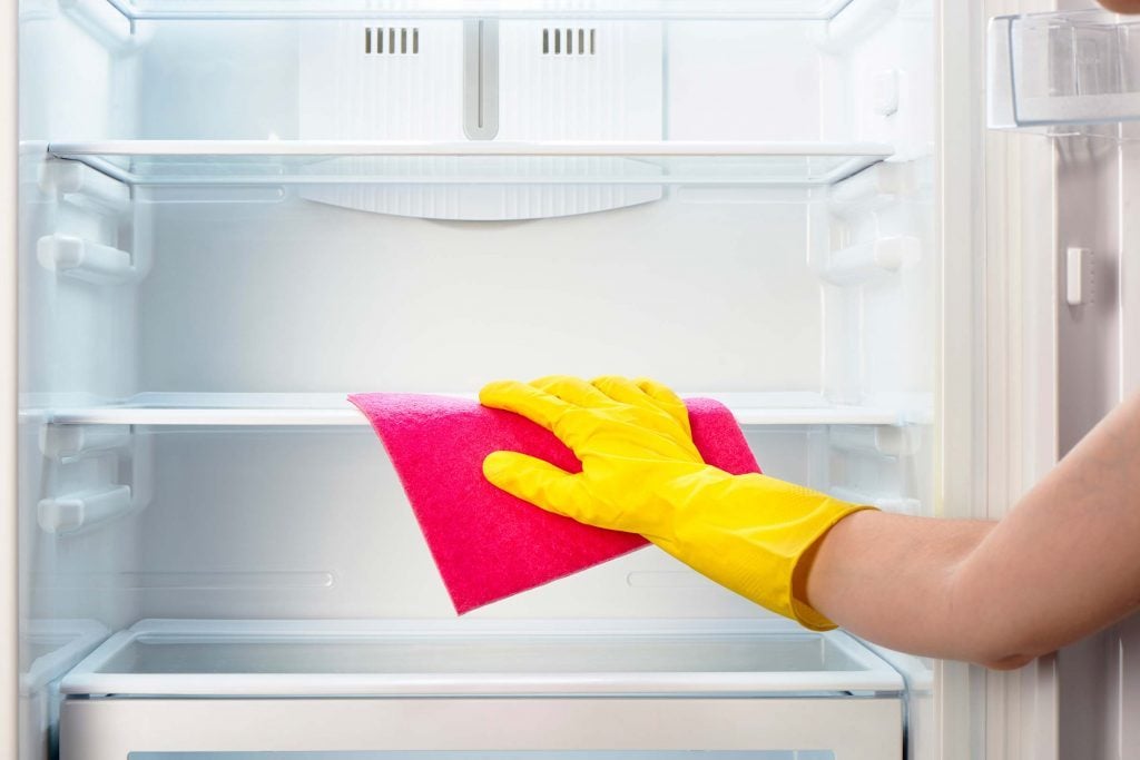 Cleaning shelves inside a refrigerator.