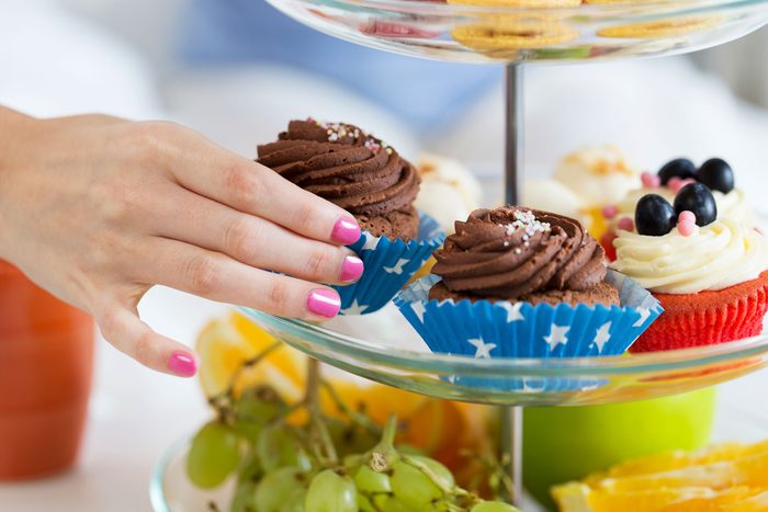 woman's hand grabbing a cupcake from a stacked tray