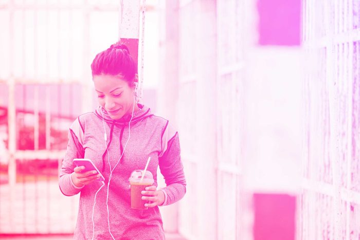 woman in exercise gear checking her smartphone outdoors