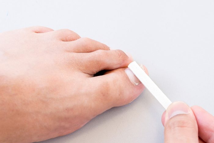 Man holding a small white ruler up to his big toe