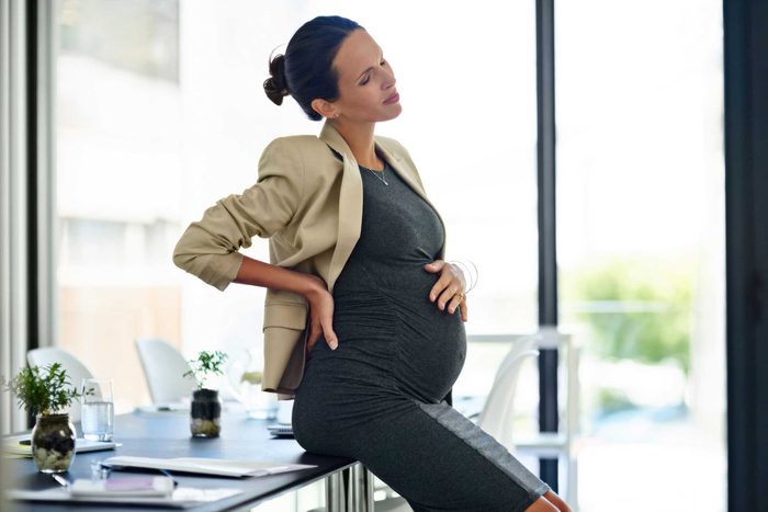 pregnant woman sitting on desk in office