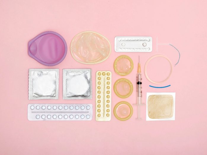variety of birth control methods on pink background