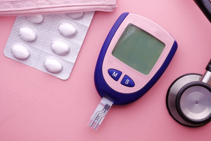 diabetes tools, stethoscope, and medication on pink background