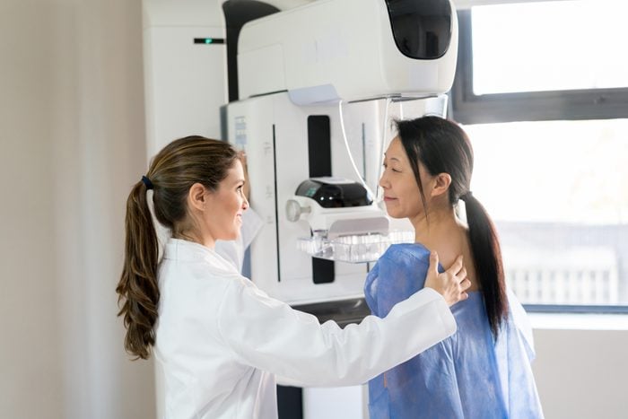 technician performing a mammogram on a patient