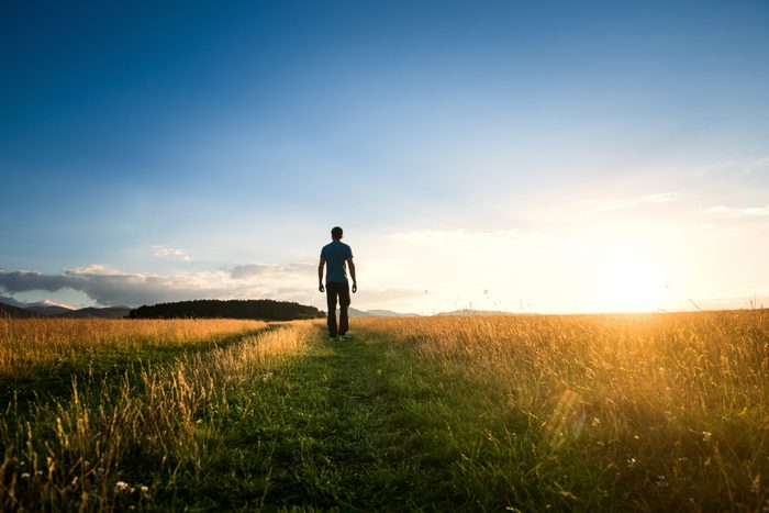 man walking alone through field enjoying nature and the outdoors