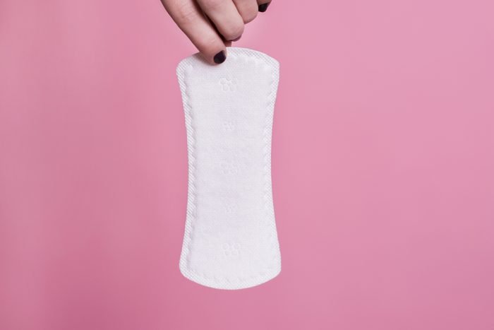 woman holding a sanitary pad on pink background