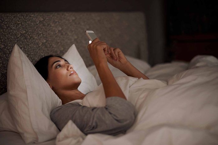 woman reading a smart phone in bed at night