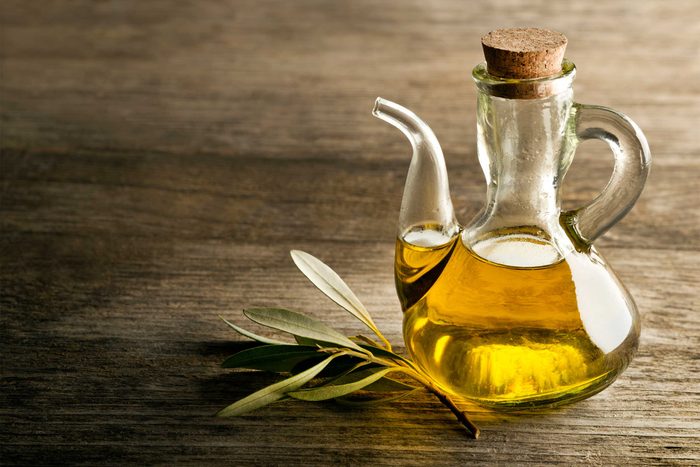 glass olive oil pourer filled with olive oil