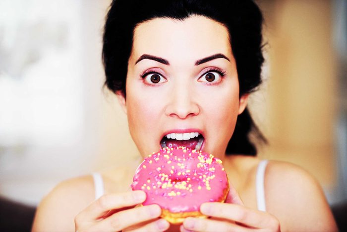 woman eating pink donut