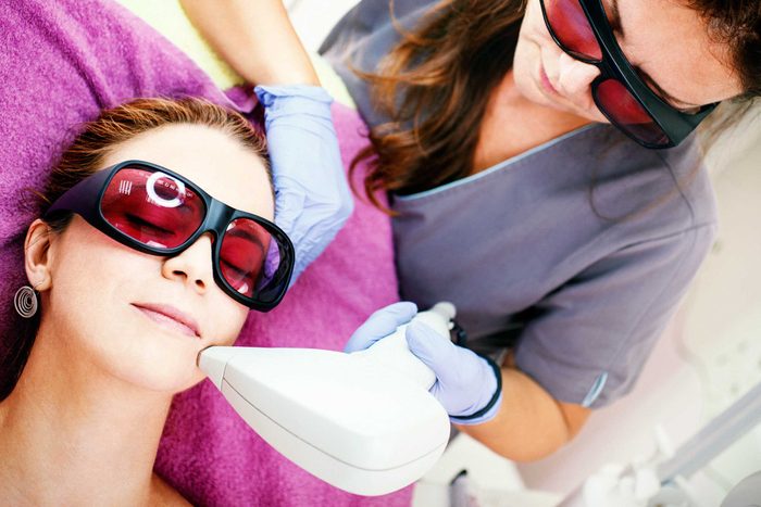 woman and doctor wearing protective glasses; the patient is getting laser skin treatment