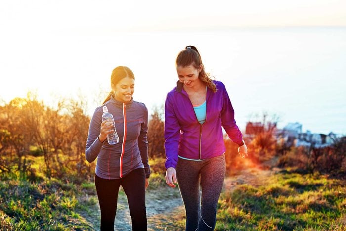 two women hiking up hill at sunset