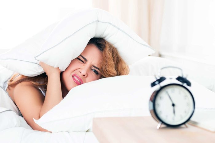 woman looking at alarm clock 