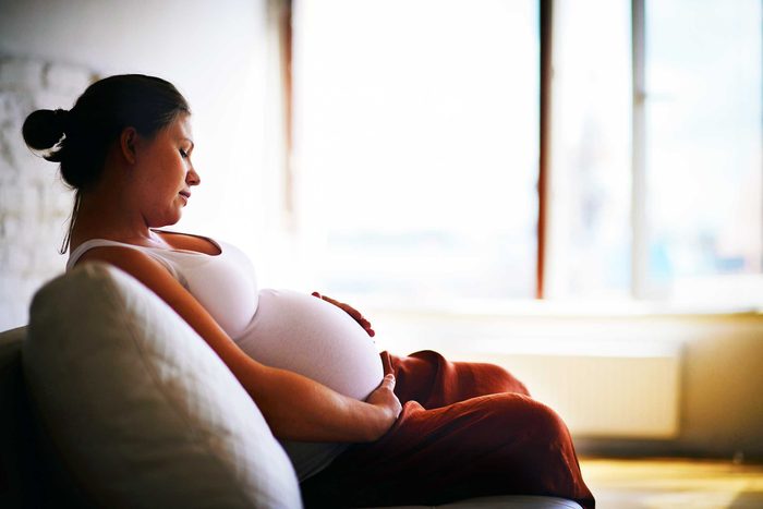 contemplative pregnant woman on couch