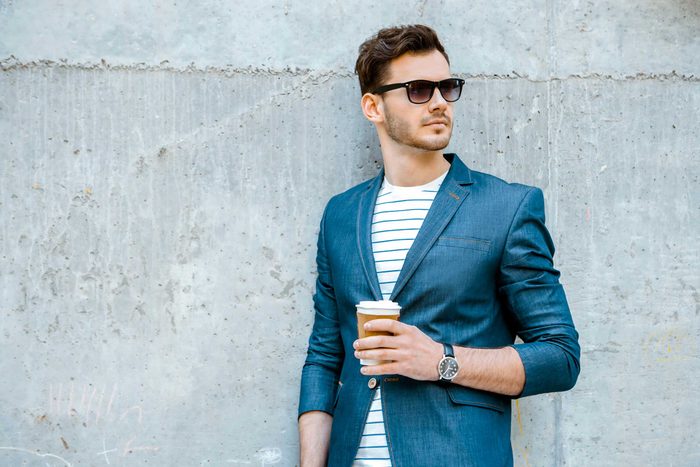 man wearing sunglasses and holding cup of coffee