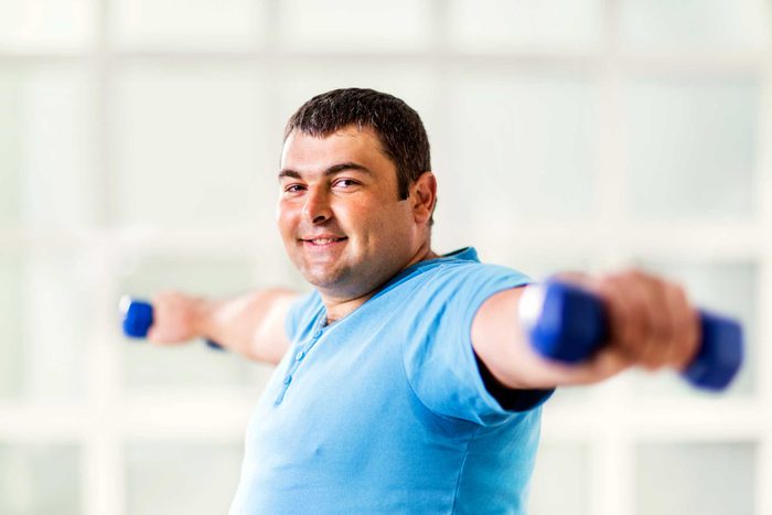 heavy man lifting dumbbells out to his sides