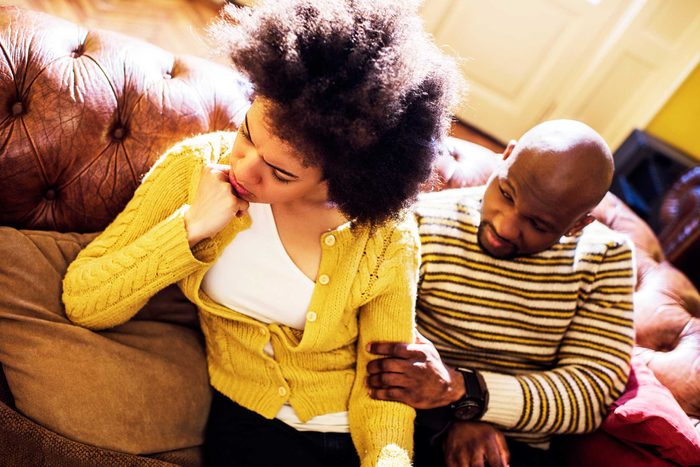 couple on couch, man holding upset woman's arm
