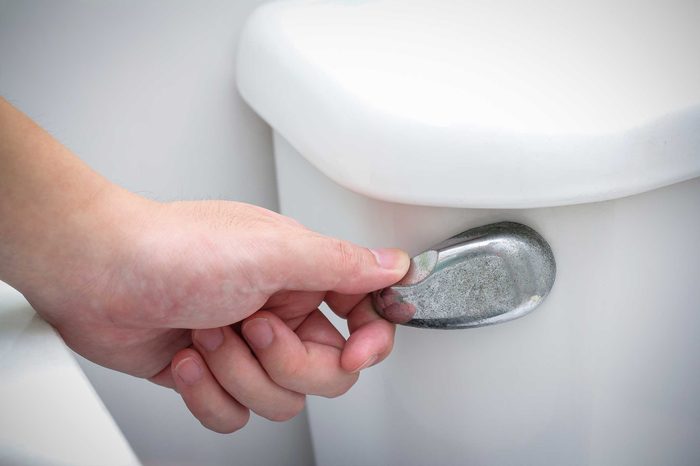 Woman flushing a toilet