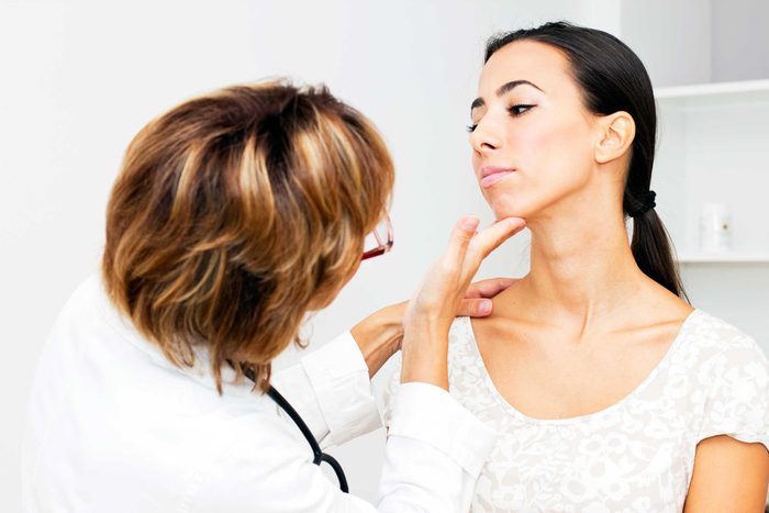 doctor checking a woman's chin and throat