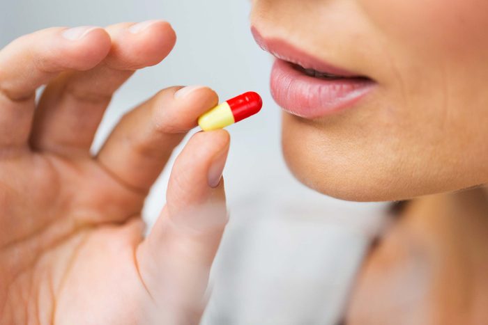closeup of a woman about to take an antibiotic pill