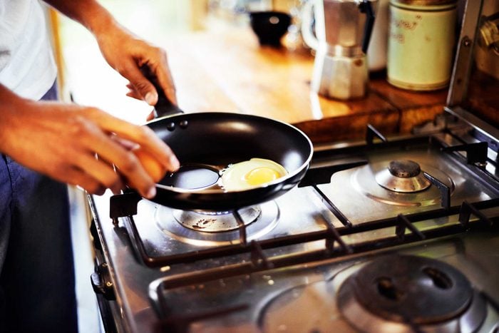 man cooking eggs in a skillet on a stove