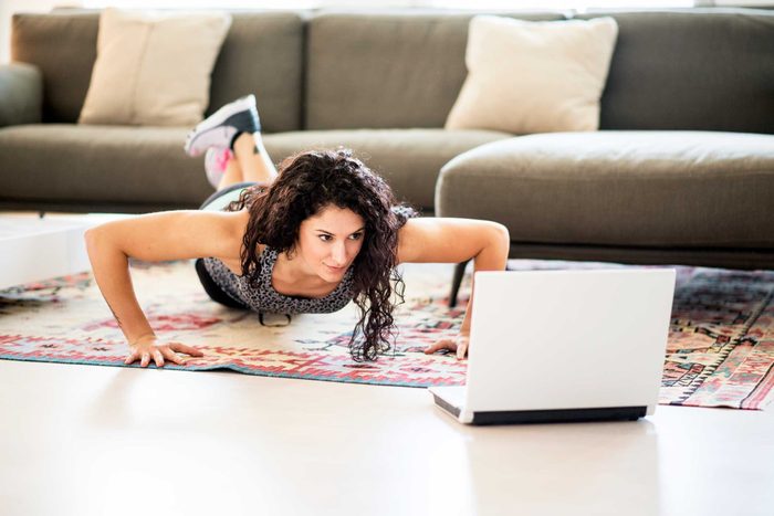 woman doing modified pushups while following a workout on computer