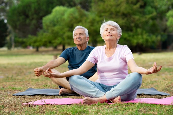 senior couple doing yoga deep breathing outside together