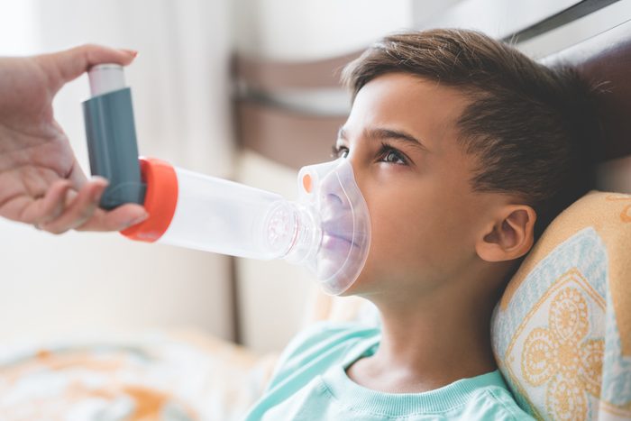 young boy using inhaler for asthma