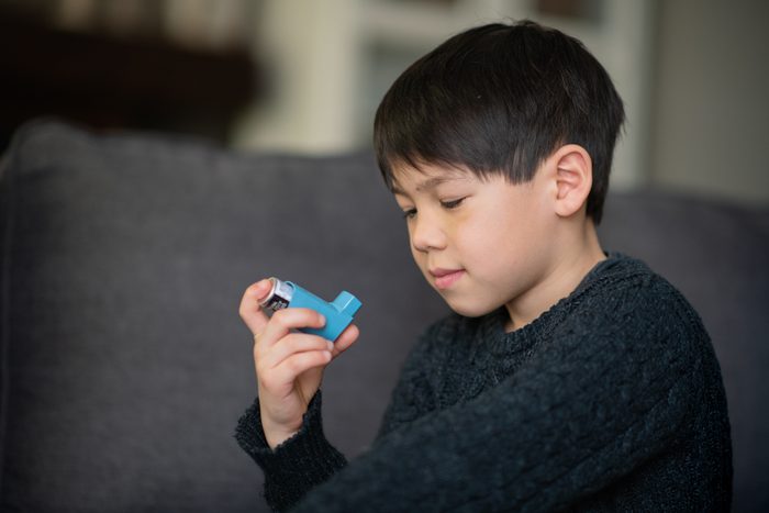 young boy holding a blue inhaler