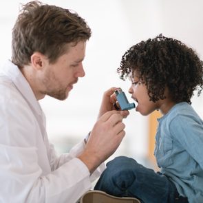 doctor teaching young boy how to use inhaler