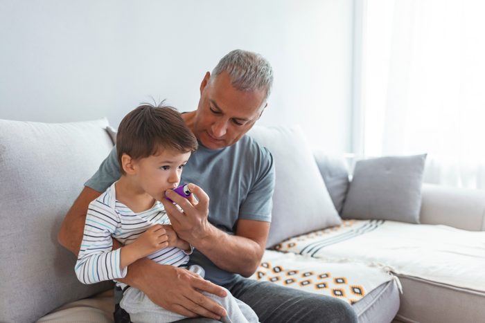 dad helping young son with inhaler for asthma