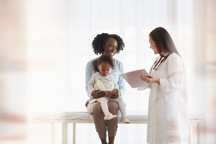 mother holding daughter while talking to doctor