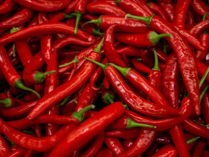 Close up of group of red chili peppers with green stems