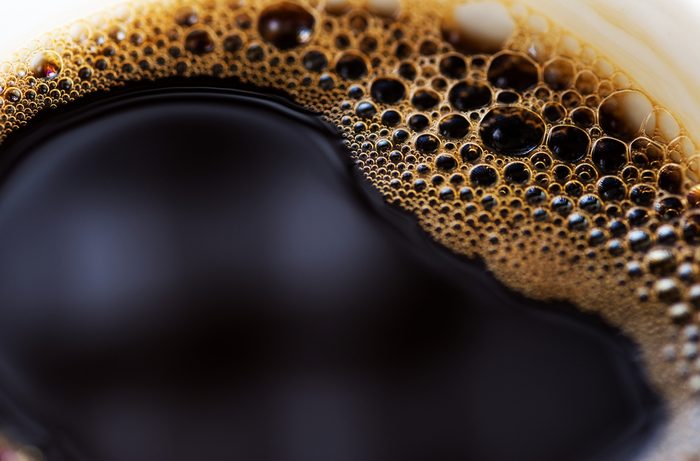 Close up of cup of black coffee with foam on side