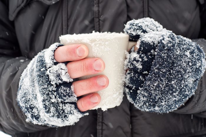 hands with snowy fingerless gloves clutching a mug 