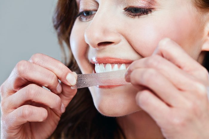 woman applying a teeth-whitening strip